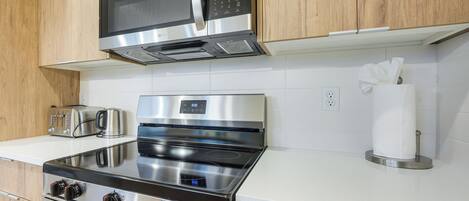 A kitchen with stainless steel appliances, a microwave, a toaster, and a paper towel holder.