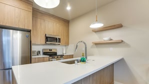 Een moderne keuken met houten kastjes, roestvrijstalen apparatuur, een wit aanrechtblad en een geïntegreerde spoelbak.