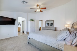 A bedroom with a bed, a ceiling fan, a TV mounted on the wall, a dresser, and a mirror. - Swim, Golf, Unwind! Queen Creek Home w/ Patio (Queen Creek)