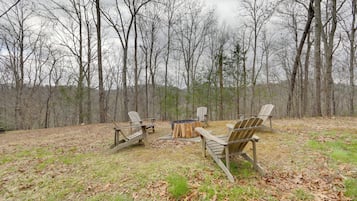 Un camping con cuatro sillas de madera tipo Adirondack dispuestas alrededor de una fogata central.