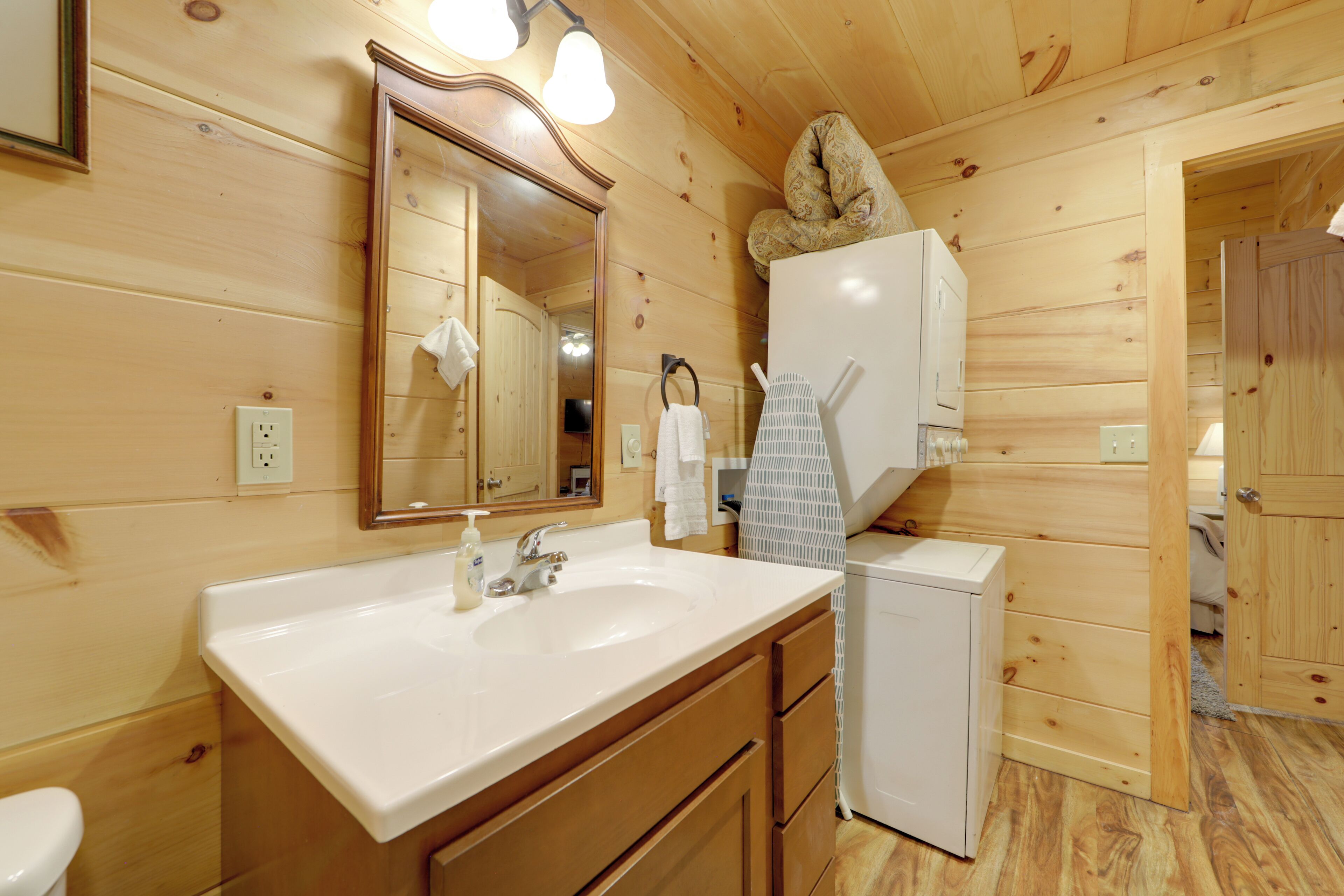 Interior d'una cabana de fusta amb bany que inclou un rentaplat, mirall i un nevera petita.