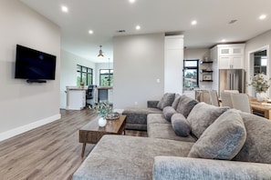 A modern living room with a sectional sofa, a coffee table, and a TV mounted on the wall.