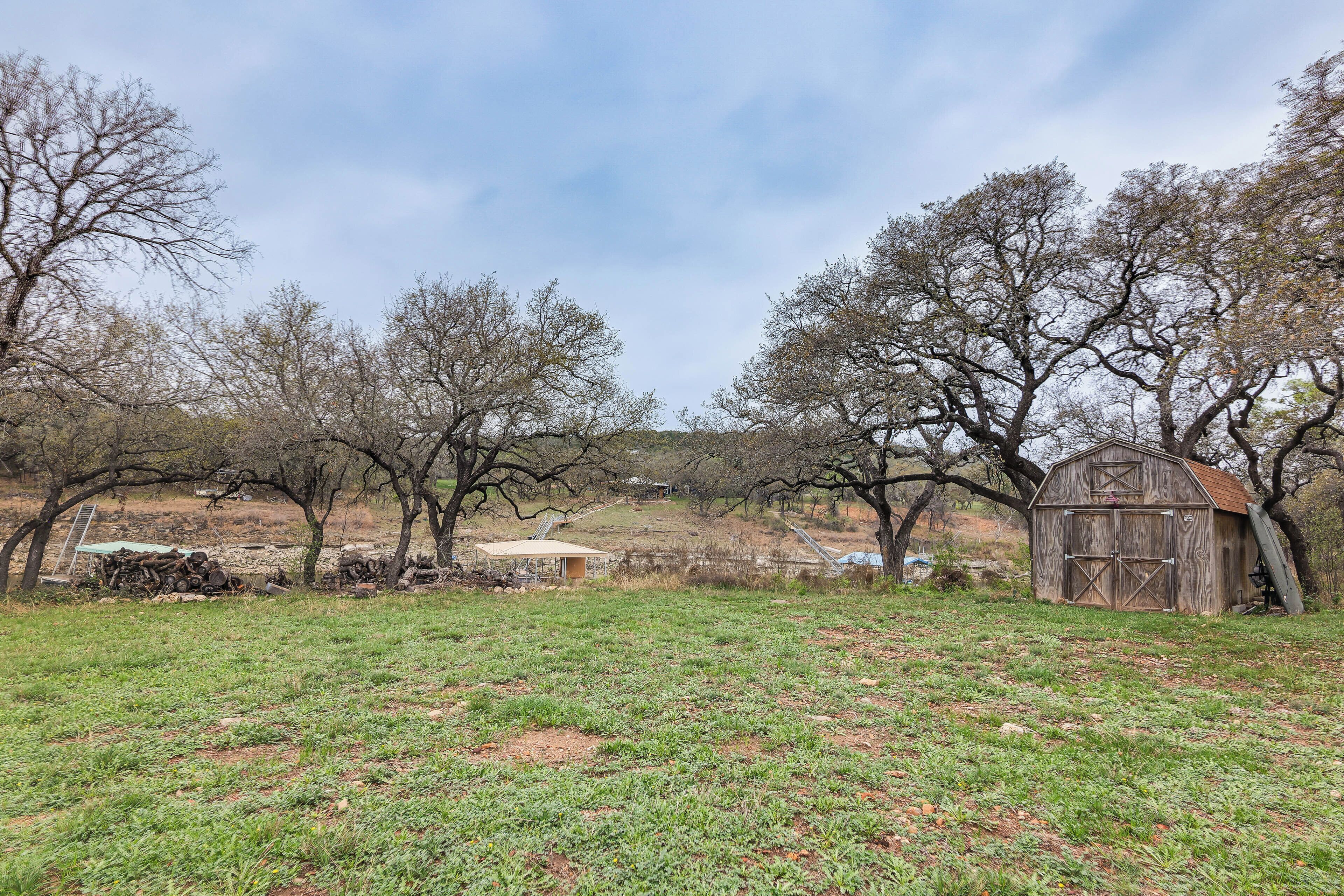 A rural landscape with a barn, trees, and a grassy field.