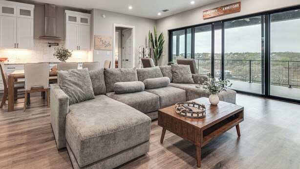 A modern living room with a sectional sofa, a wooden coffee table, and a large window with a city view. - Hot Tub, Lake View! Lakefront Marble Falls Home (Marble Falls)