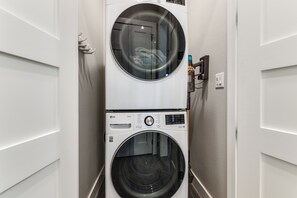 Une buanderie équipée de deux machines à laver superposées, d’un panneau de commande et d’une prise de courant.