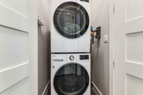 A laundry room with two stacked washing machines, a control panel, and a power outlet. - Hot Tub, Dock & View! Lakefront Marble Falls Home (Marble Falls)