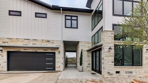 A modern two-story house with a garage, stone facade, and large windows. - Hot Tub, Lake View! Lakefront Marble Falls Home (Marble Falls)