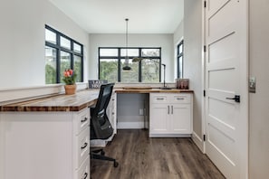 A modern kitchen with white cabinets, a wooden countertop, a black office chair, and a sign reading 'LAKE HOUSE.' - Hot Tub, Dock & View! Lakefront Marble Falls Home (Marble Falls)