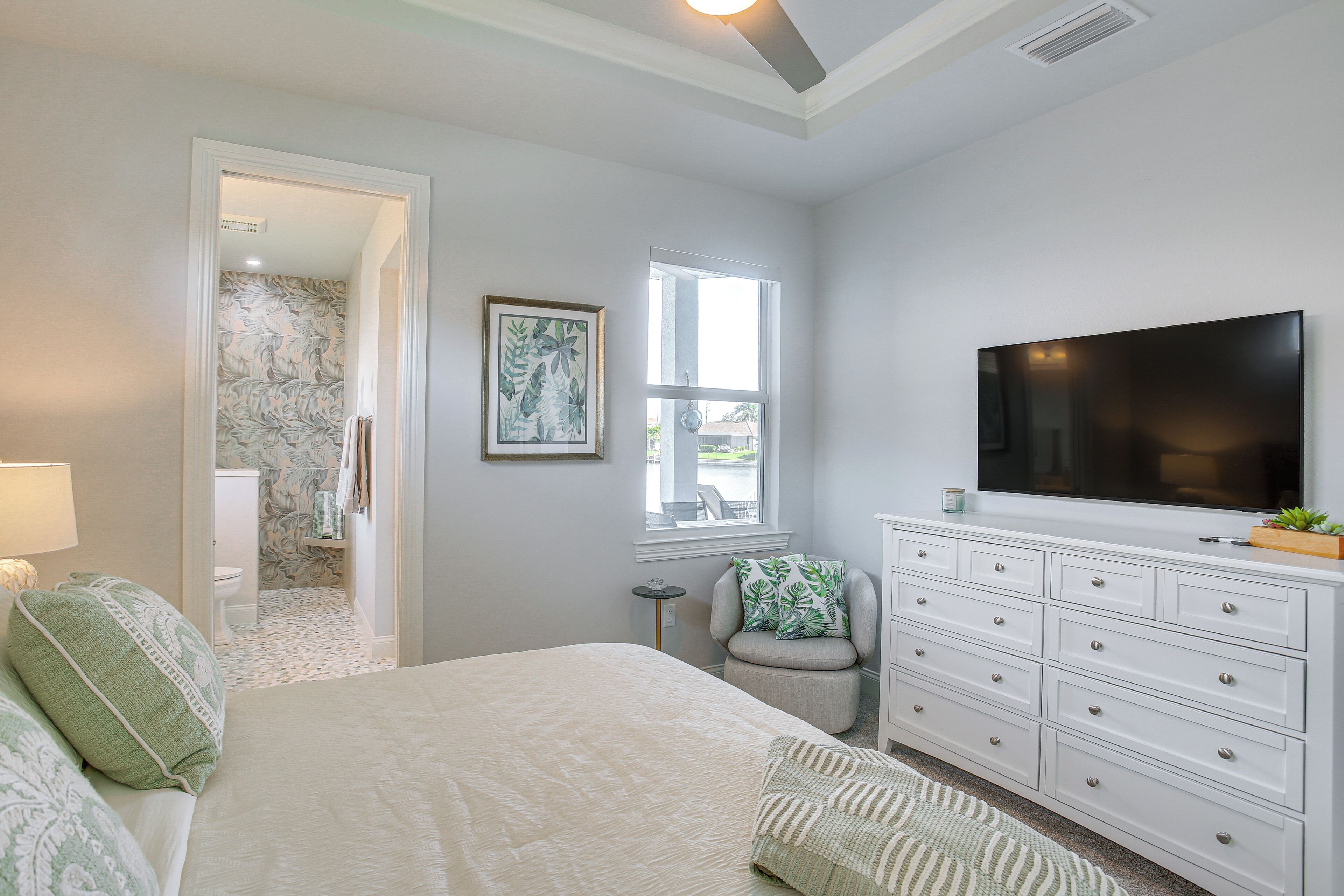 Une chambre à coucher avec un lit, une télévision, une commode, une chaise et une fenêtre.
