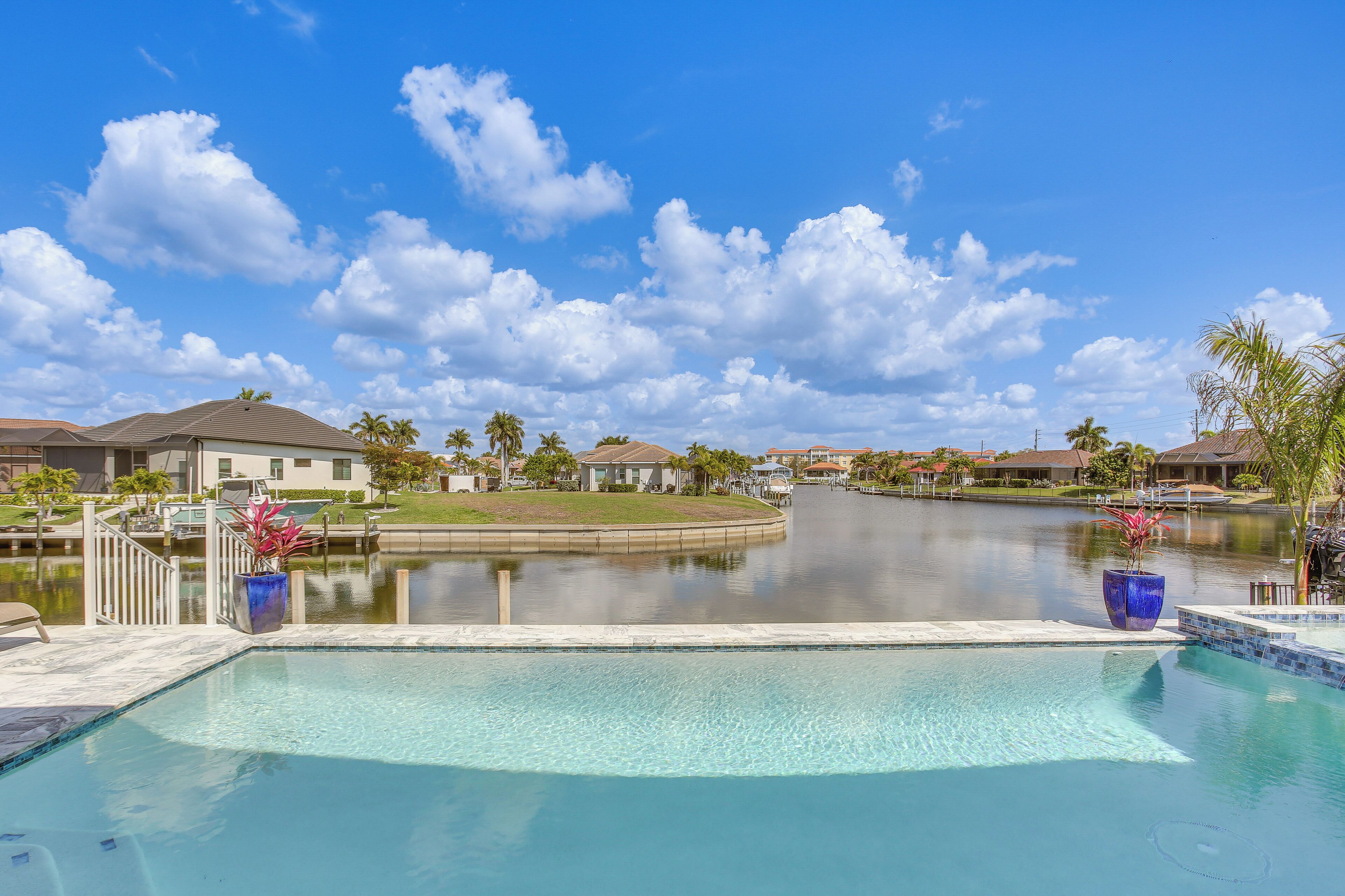 A residential area with a swimming pool, houses, and a calm body of water.
