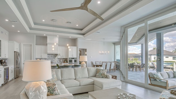 A spacious living area with a large sectional sofa, a coffee table, and a dining area with a view. - Luxe Canal-front Getaway w/ Pool in Punta Gorda! (Punta Gorda)