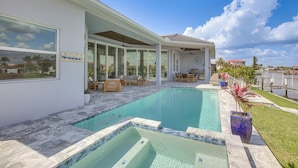 A modern house with a swimming pool, outdoor seating, and a view of the water. - Luxe Canal-front Getaway w/ Pool in Punta Gorda! (Punta Gorda)
