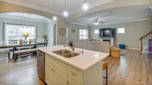 Una cocina amplia con una isla grande, luces colgantes y un comedor con muebles de madera.