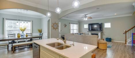 A spacious kitchen with a large island, pendant lights, and a dining area with wooden furniture.