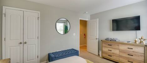 A bedroom with a bed, a dresser, a television, and a mirror.