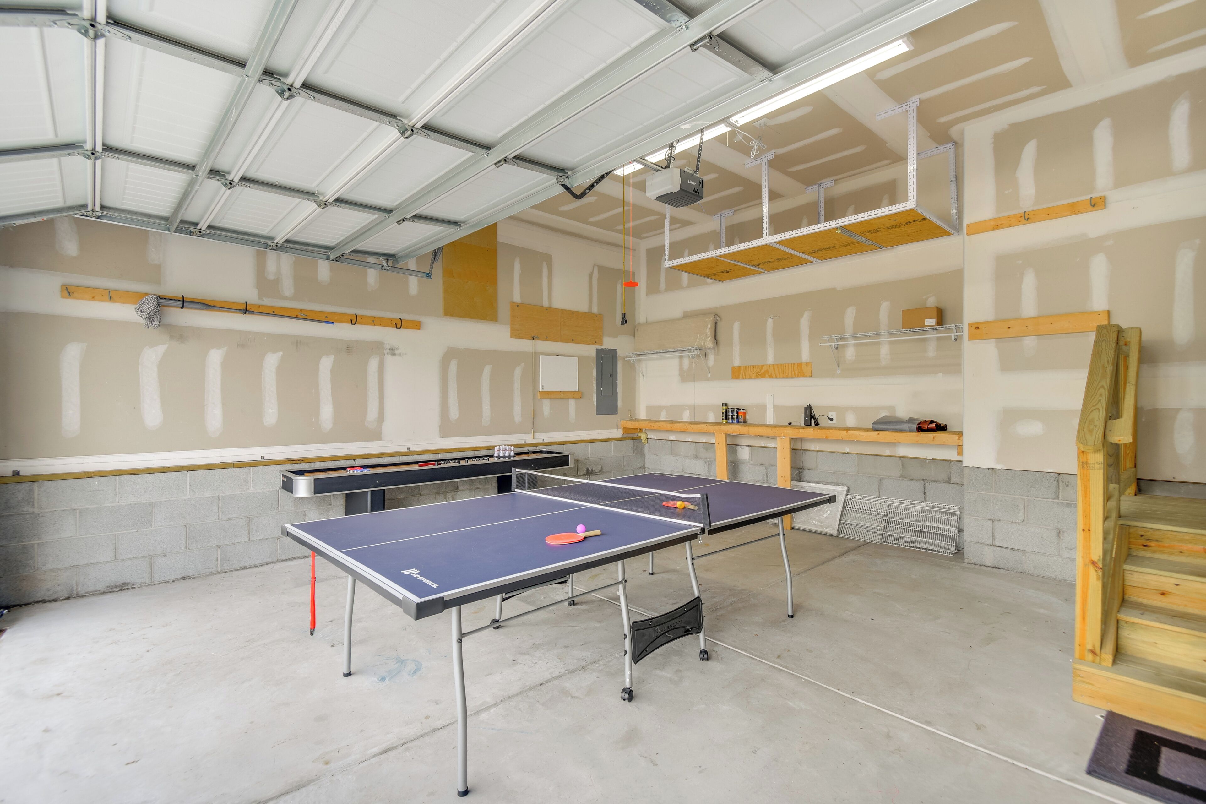 A spacious indoor area with two ping pong tables, a concrete floor, and exposed ceiling structures.