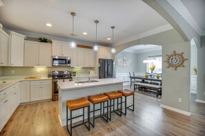 A modern kitchen with white cabinets, a central island with bar stools, stainless steel appliances, pendant lighting, and a view into the dining area. - 2 Blks to Beach! Family Home w/ Hot Tub in Norfolk (Norfolk)