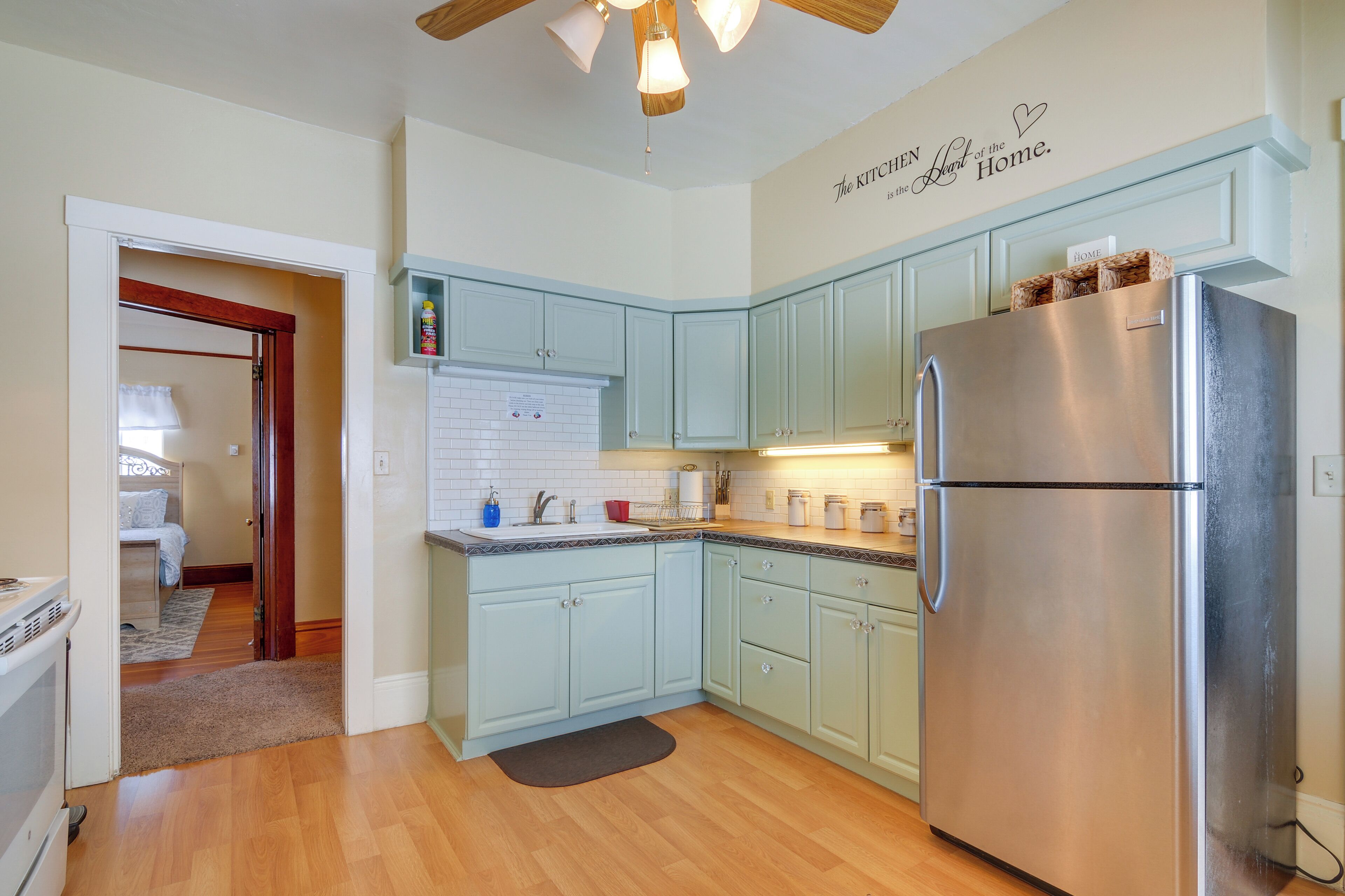 Una cocina moderna con armarios azul claro, un refrigerador de acero inoxidable y un ventilador de techo.