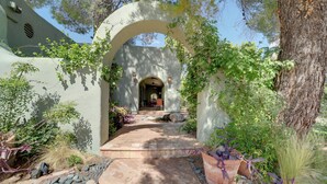 An arched entrance with a stone pathway leading to a building, surrounded by greenery and a tree. - Group Retreat on Flower Farm Near Sedona Trails (Cornville)