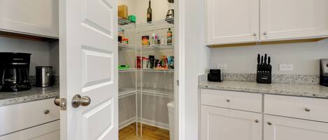 A kitchen with white cabinets, a coffee maker, and a spice rack.