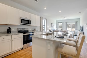 A modern kitchen with white cabinets, stainless steel appliances, and a central island with seating.