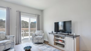 En moderne stue med sofa, lænestol, fjernsyn og et træsofabord.