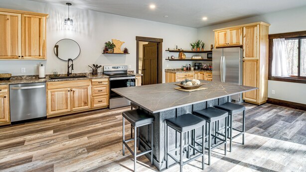 A modern kitchen with wooden cabinets, a central island with bar stools, stainless steel appliances, and a large window. - 4 Mi to Golf: Family Home in Nisswa, Near Lakes! (Nisswa)