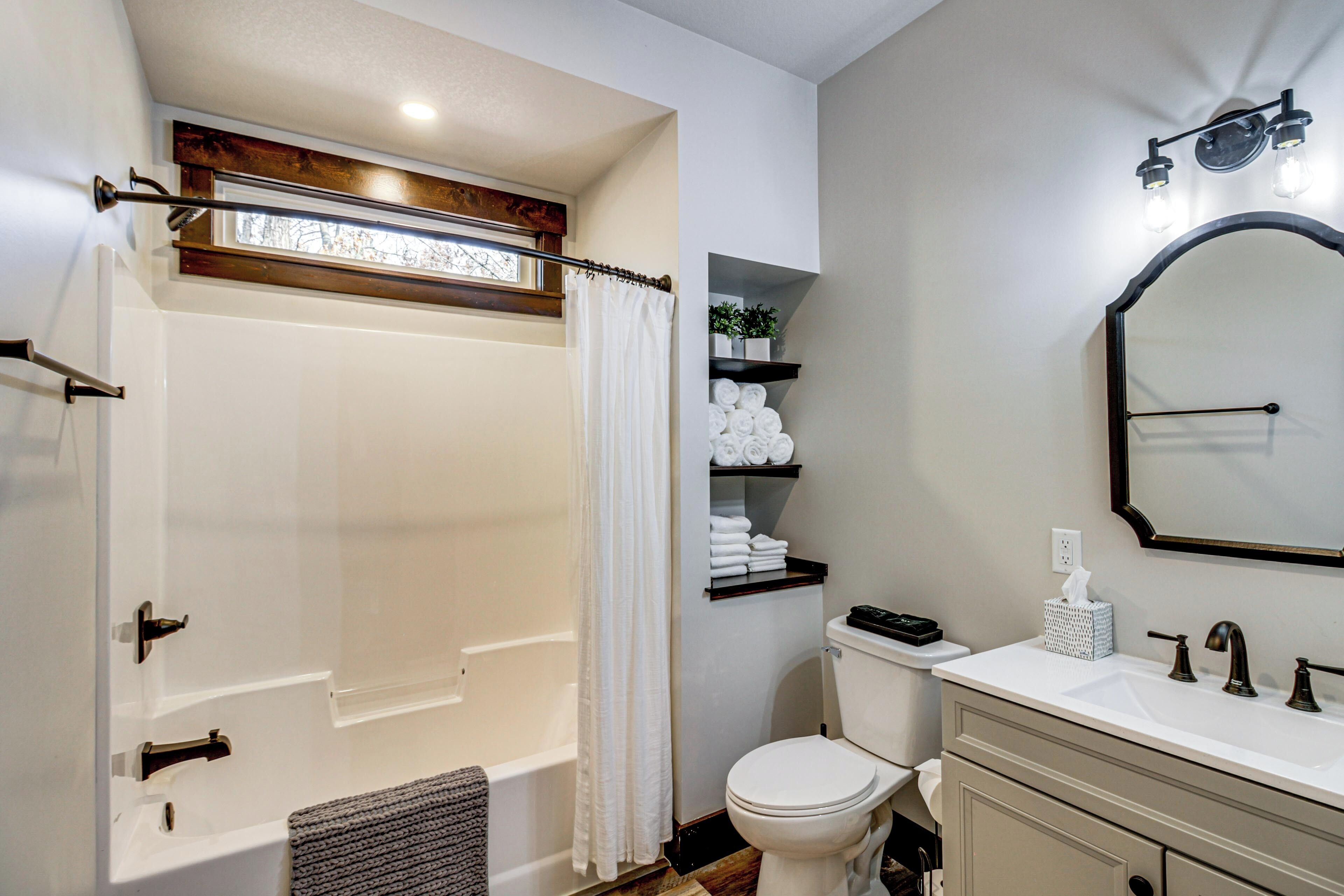 A bathroom with a bathtub, toilet, vanity, and a mirror.