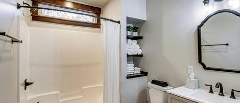 A bathroom with a bathtub, toilet, vanity, and a mirror.