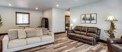 Una sala de estar con un sofá beige, un sofá de cuero marrón y suelo de madera.
