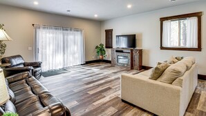 A living room with a dark leather sofa, a beige armchair, a television, and a fireplace. - 4 Mi to Golf: Family Home in Nisswa, Near Lakes! (Nisswa)