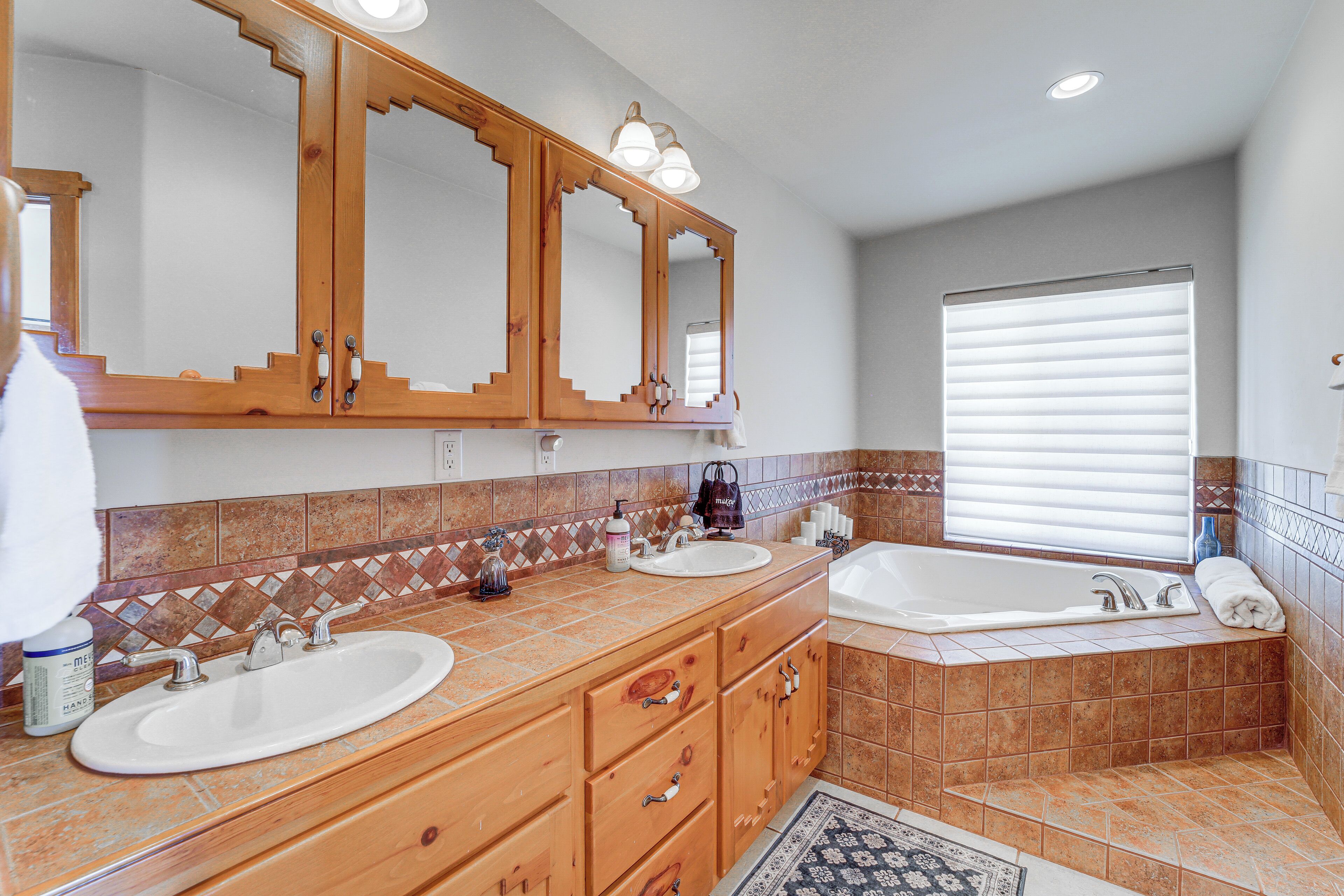 A bathroom with two sinks, a large mirror, and a bathtub.