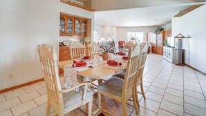 Un coin repas avec une table et des chaises en bois, un ventilateur de plafond et une cuisine en arrière-plan.