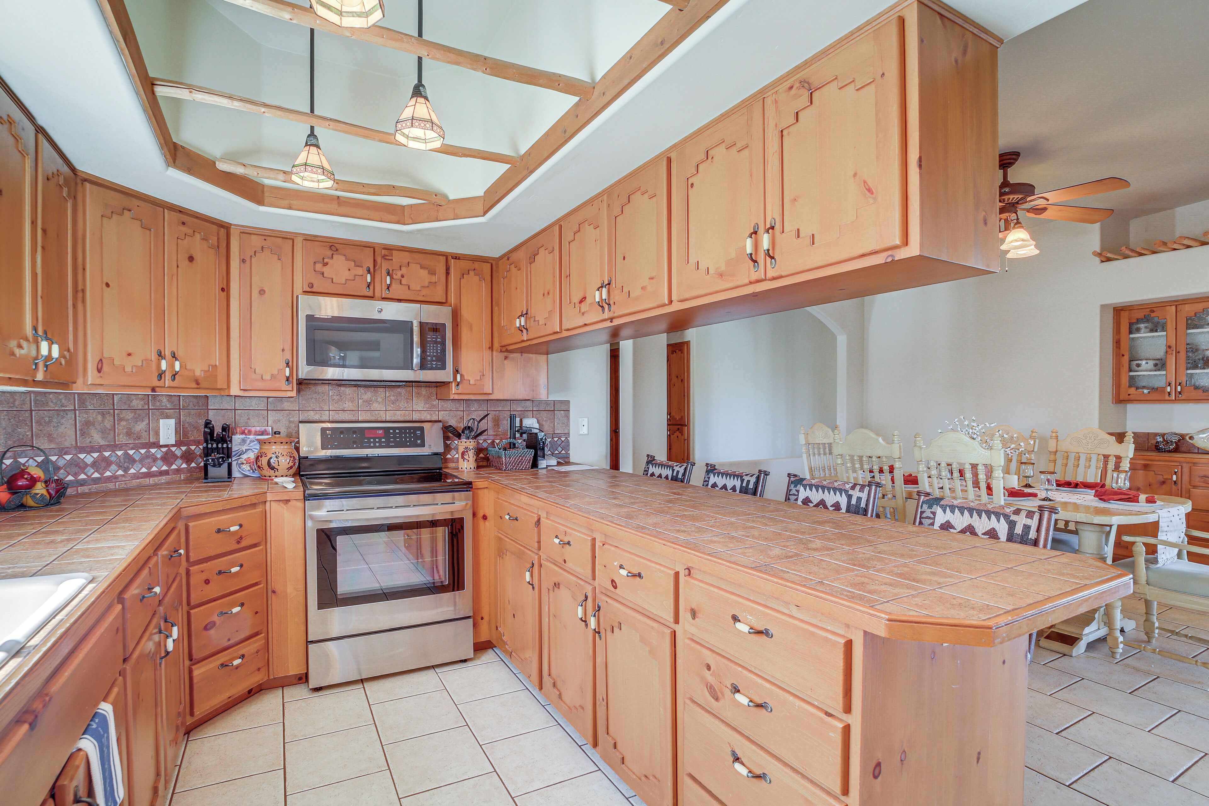 A spacious kitchen with wooden cabinets, a large island, and a dining area with chairs and a table.