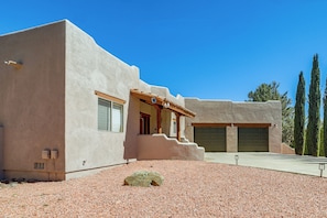 A modern building with a stucco exterior, a covered porch, and a gravel driveway.