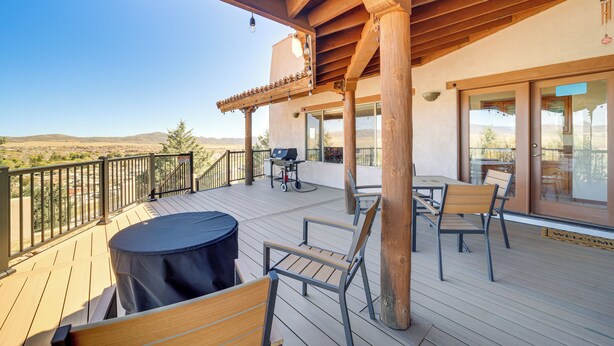 Une terrasse en bois, dotée de mobilier d’extérieur, d’un barbecue et offrant une vue sur le paysage.