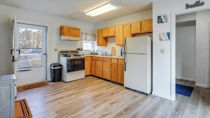 A compact kitchen with wooden cabinets, a refrigerator, a stove, and a window. - Pet-friendly Home w/ Patio: 4 Mi to Saratoga Spa! (Saratoga Springs)