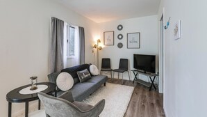A living room with a sofa, chairs, a TV, a lamp, and wall art. - Pet-friendly Home w/ Patio: 4 Mi to Saratoga Spa! (Saratoga Springs)