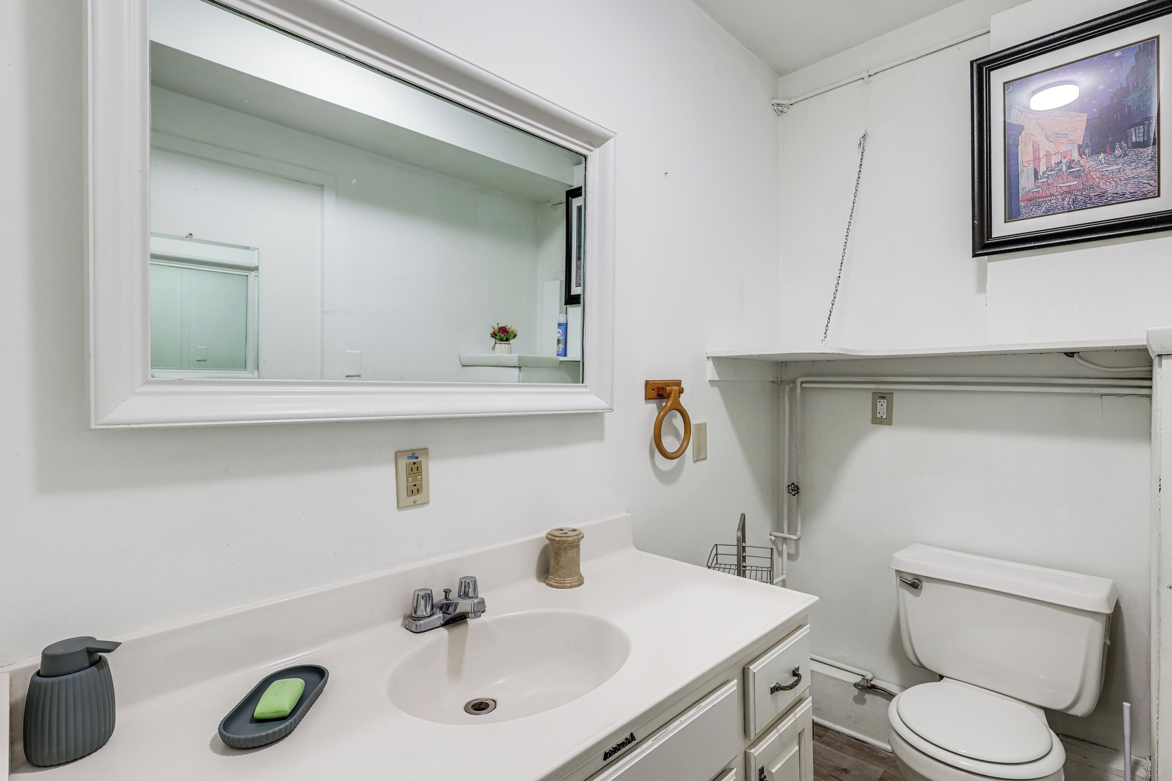 A bathroom with a white sink, mirror, and toilet.