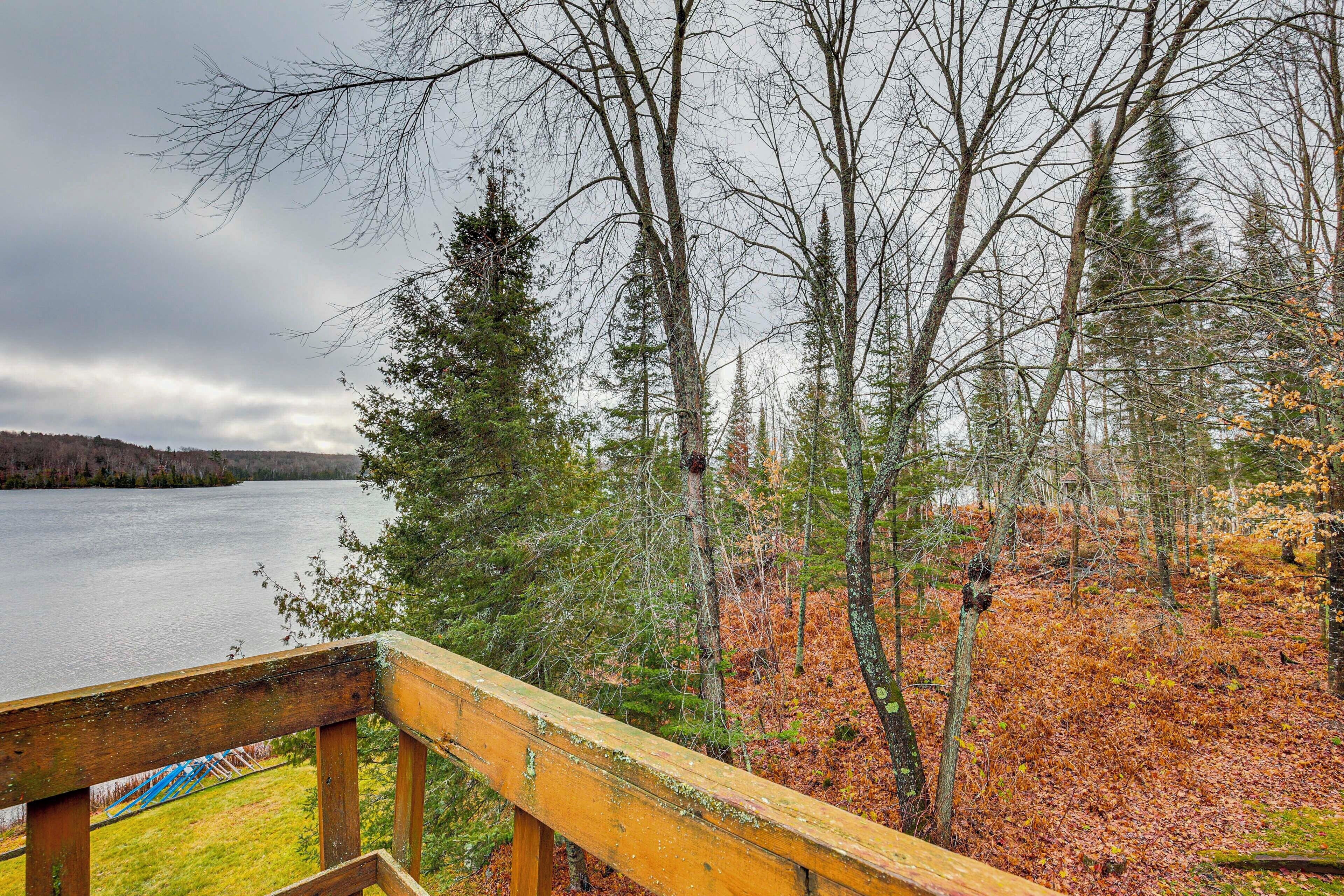 A wooden deck overlooking a lake with trees and a grassy area.