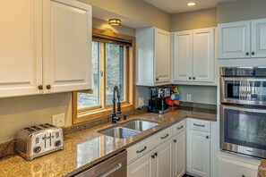 A kitchen with white cabinets, a granite countertop, a toaster, a coffee maker, and a double oven. - Sauna & Pool Table: Family Home on Lake Chicagon (Iron River)