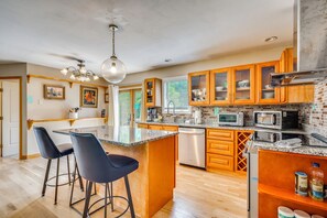 A modern kitchen with granite countertops, stainless steel appliances, and wooden cabinetry. - Explore the White Mountains! Spacious Rural Home (Thornton)