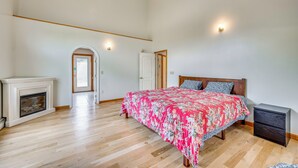 A bedroom with a large bed, a fireplace, and a door leading to another room. - Explore the White Mountains! Spacious Rural Home (Thornton)