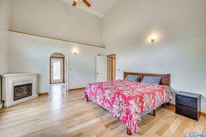 A bedroom with a large bed, a fireplace, and a door leading to another room. - Explore the White Mountains! Spacious Rural Home (Thornton)