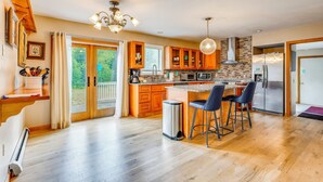 Eine moderne Küche mit Holzausstattung, einem Edelstahlkühlschrank und einer großen Kochinsel mit Barhocker.