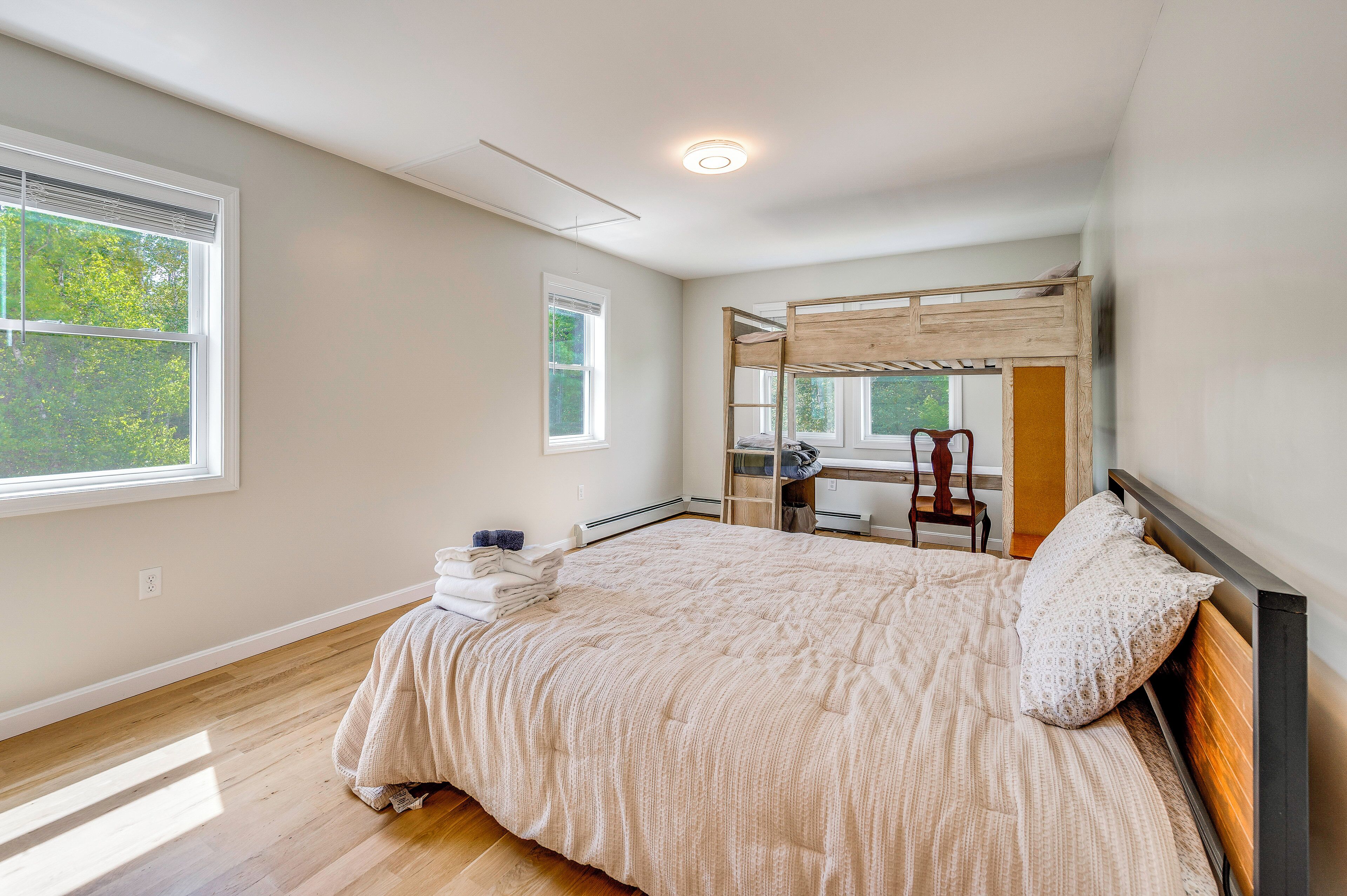 A bedroom with a large bed, a desk, and a chair.