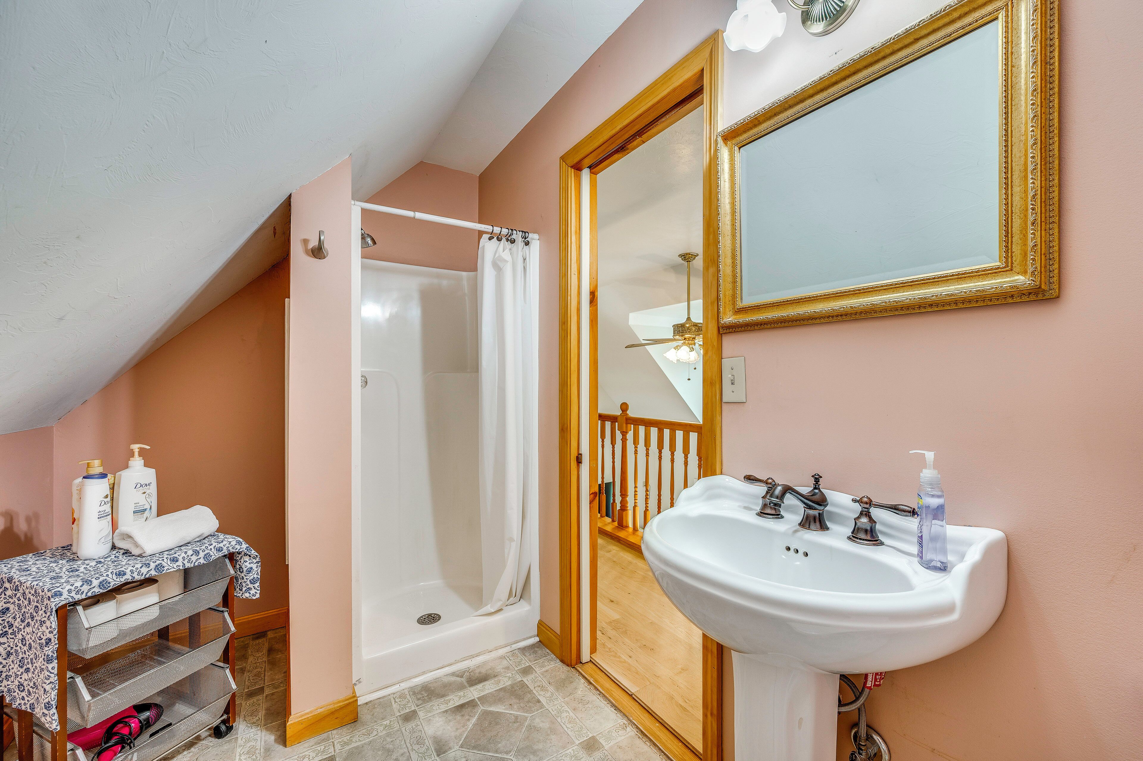 A bathroom with a shower, sink, and mirror.