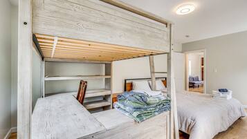 Un lit superposé avec une tête de lit en bois, une table de chevet et un lit recouvert d’une couverture blanche.