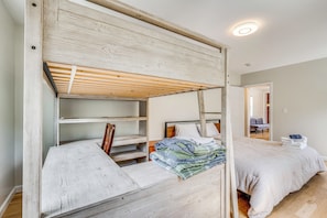 A bunk bed with a wooden headboard, a bedside table, and a bed with a white blanket.