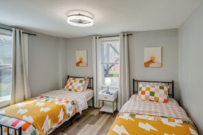 Une chambre avec deux lits, un bureau et une fenêtre avec des rideaux.